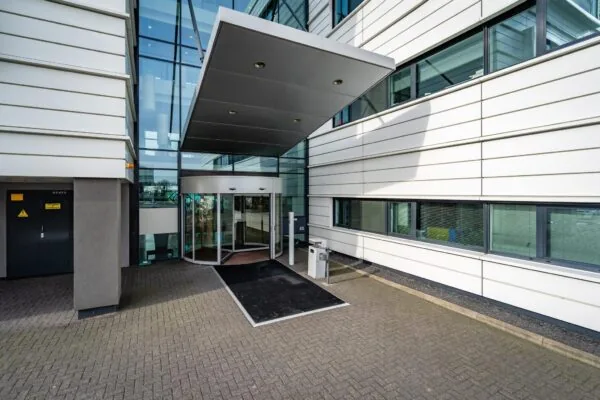 Ingang van een modern kantoorgebouw aan de Waalhaven O.Z. met een glazen gevel en draaideur.